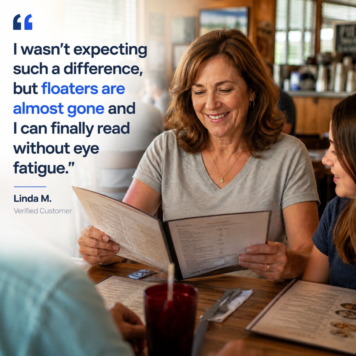 A woman in her fifties reading a restaurant menu at arm's normal distance, smiling, with family at the table. Quote from Linda M.: floaters are almost gone and I can finally read without eye fatigue.